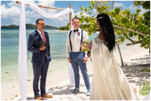 wedding minister and groom waiting under arch for bride